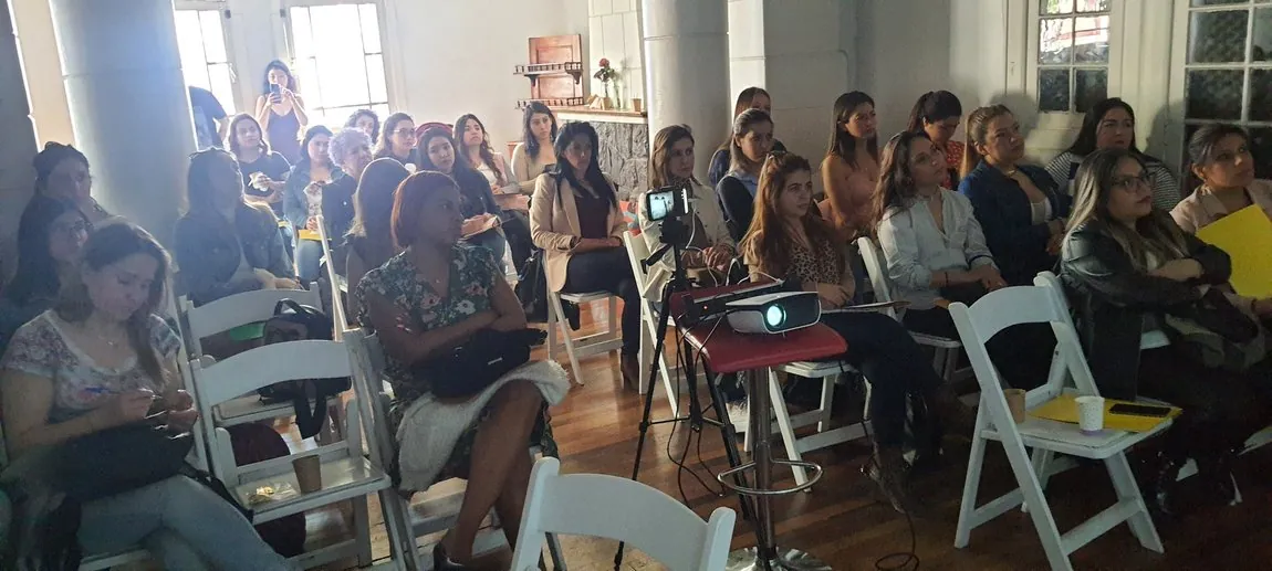Sala llena de mujeres en un encuentro presencial de Rayén Milán