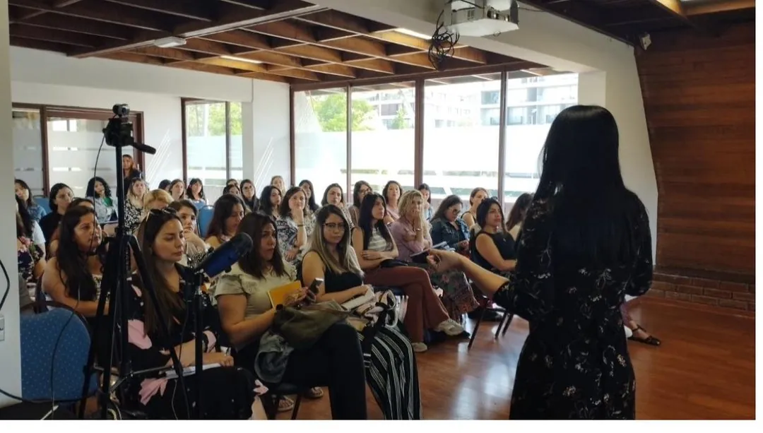 Rayén Milán de vestido negro dictando frente a la sala llena